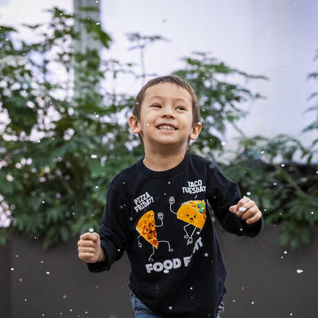 Boy happily plays under indoor snow flurries in the Academy Piazza