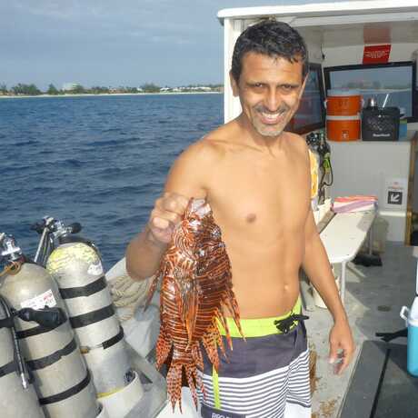 Luiz Rocha holds a caught invasive lionfish 