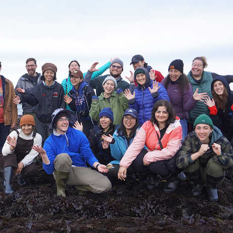 A group of students from the 2023 class pose together on Agate Beach. 