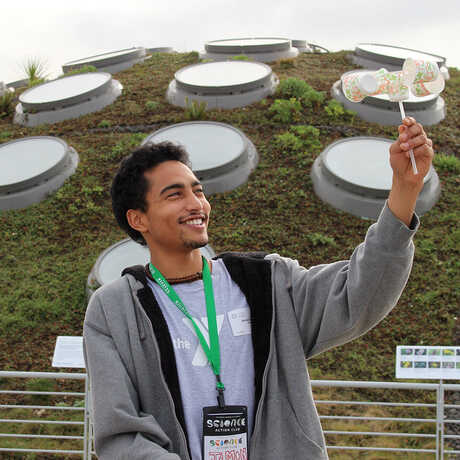 Science Action Club student uses an anemometer on Academy Living Roof
